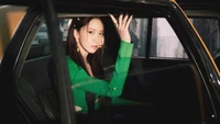 Yoona de Girls' Generation en un elegante atuendo verde, sentada en un coche, capturando la esencia del glamour del K-pop del álbum "Forever 1".