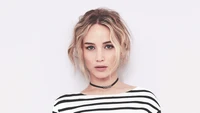 Jennifer Lawrence mit zerzausten Haaren, trägt ein gestreiftes Oberteil und eine Choker-Halskette, schaut direkt in die Kamera.