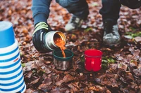 Genießen von warmen Getränken am Campingplatz zwischen Herbstblättern