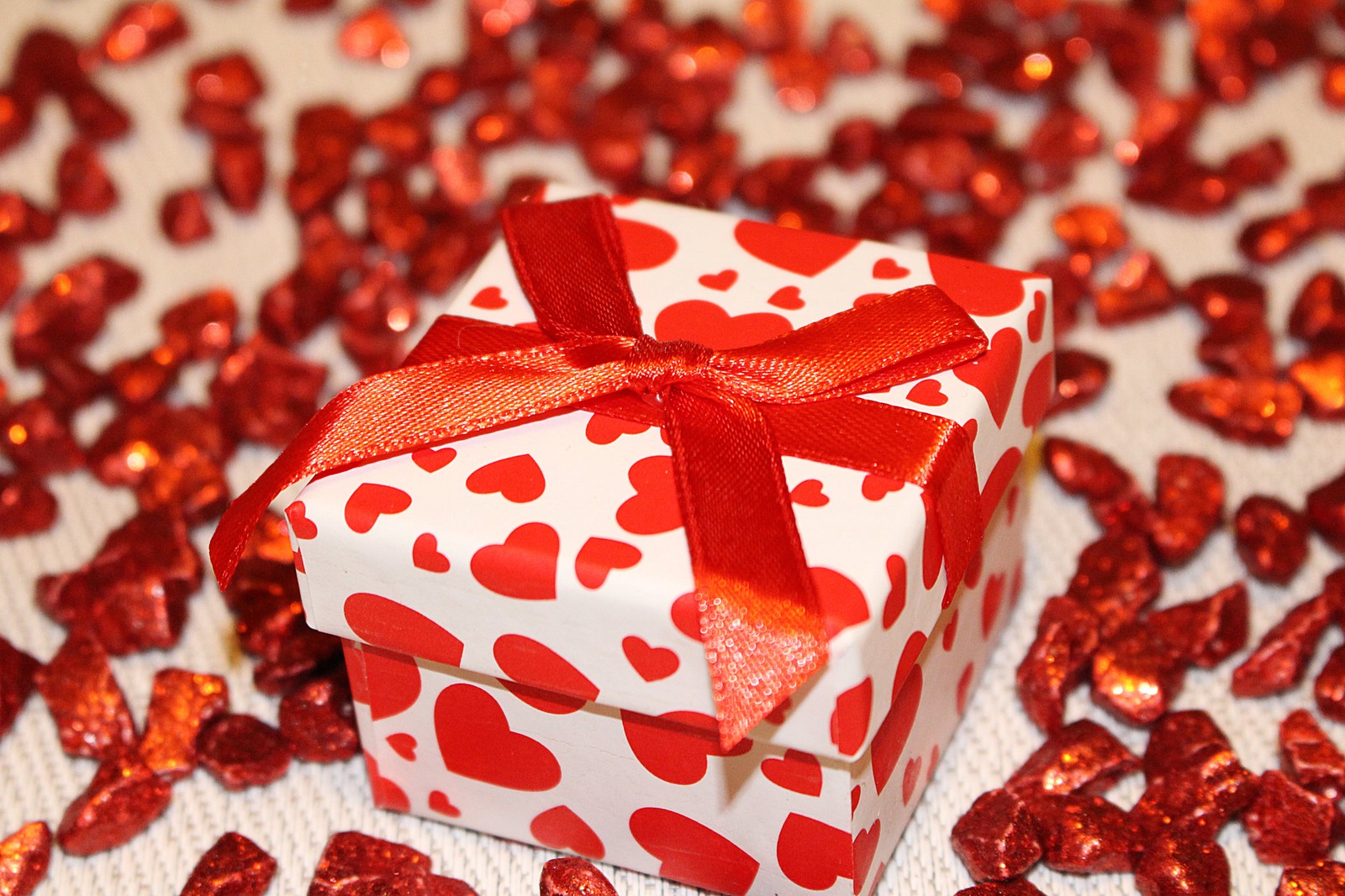 Il y a une petite boîte rouge et blanche avec un nœud rouge (cadeau, saint valentin, emballage cadeau, rouge, nourriture)