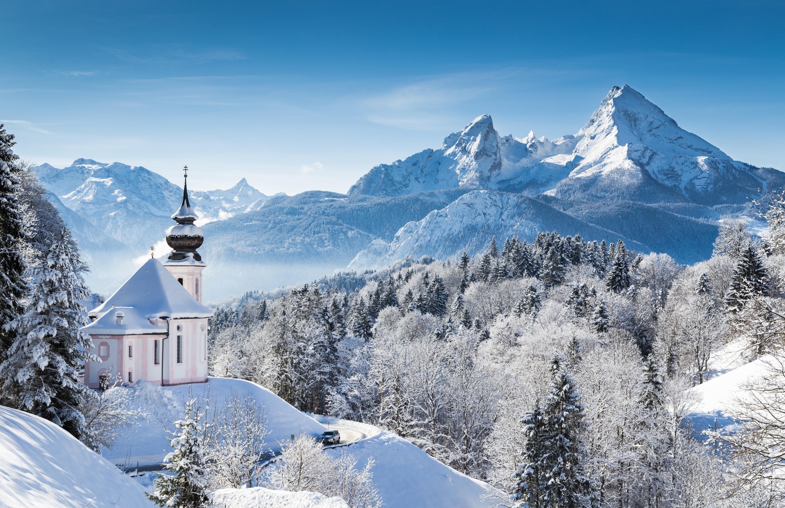 Uma igreja nas montanhas coberta de neve com vista para as montanhas (montanha, formas montanhosas, inverno, neve, cadeia de montanhas)