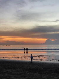 Atardecer sereno en la playa con figuras en silueta