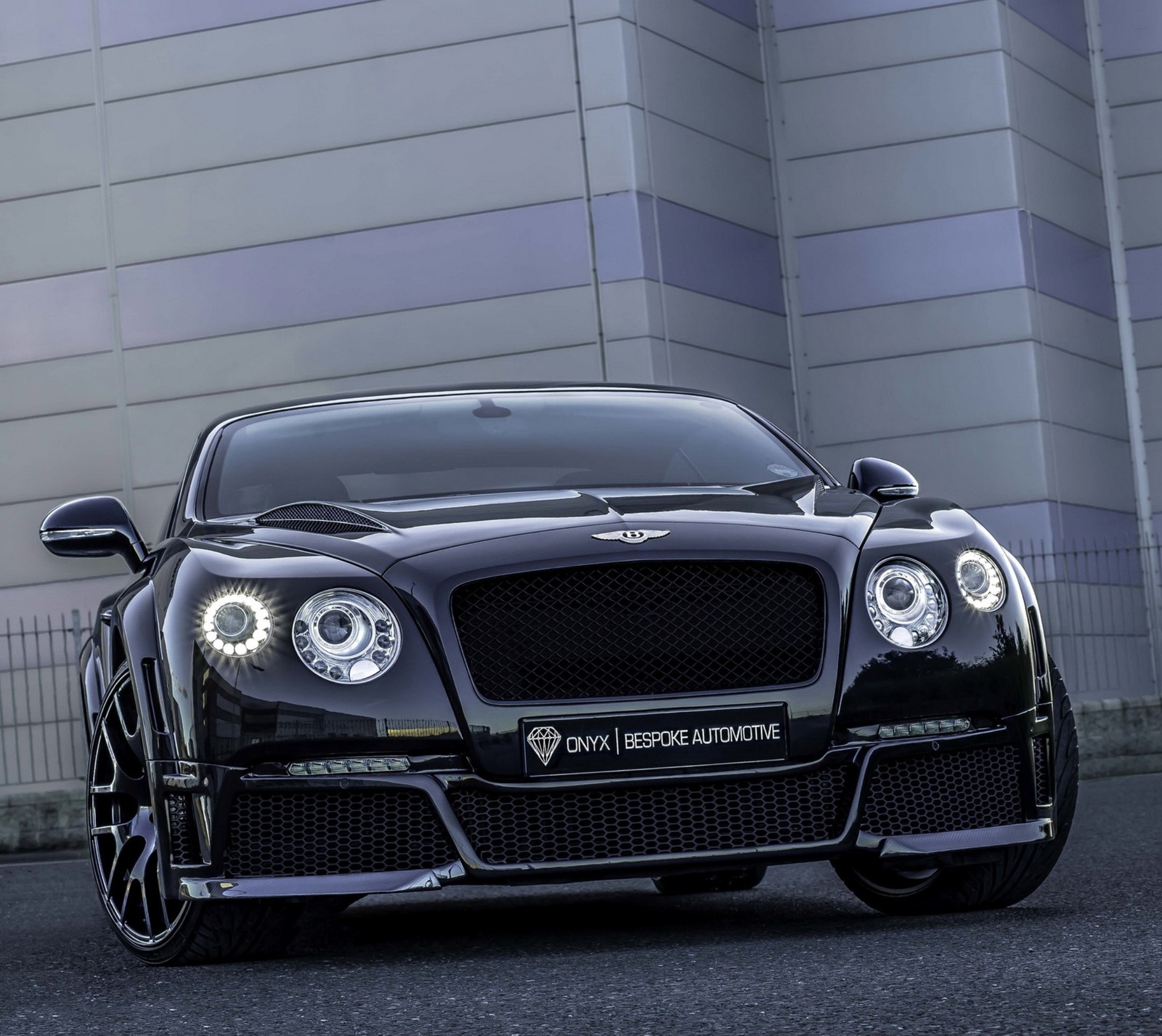 A close up of a black bentley car parked in front of a building (bentley, car, continental)