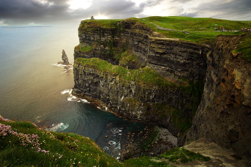 Une vue d'une falaise avec une personne se tenant au sommet (falaises de moher, falaise, galway, la côte, klippe)