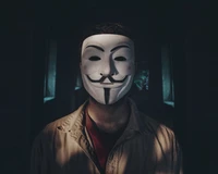 Selfie de uma pessoa usando uma máscara de Guy Fawkes, exibindo um sorriso misterioso contra um fundo escuro.