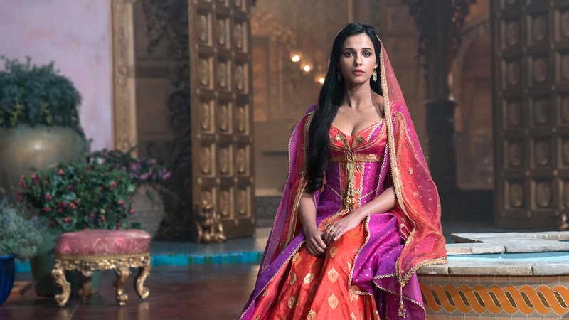 Женщина в розовом и красном платье сидит на скамейке (аладдин 2019, aladdin 2019, фильм, жасмин, наоми скотт)