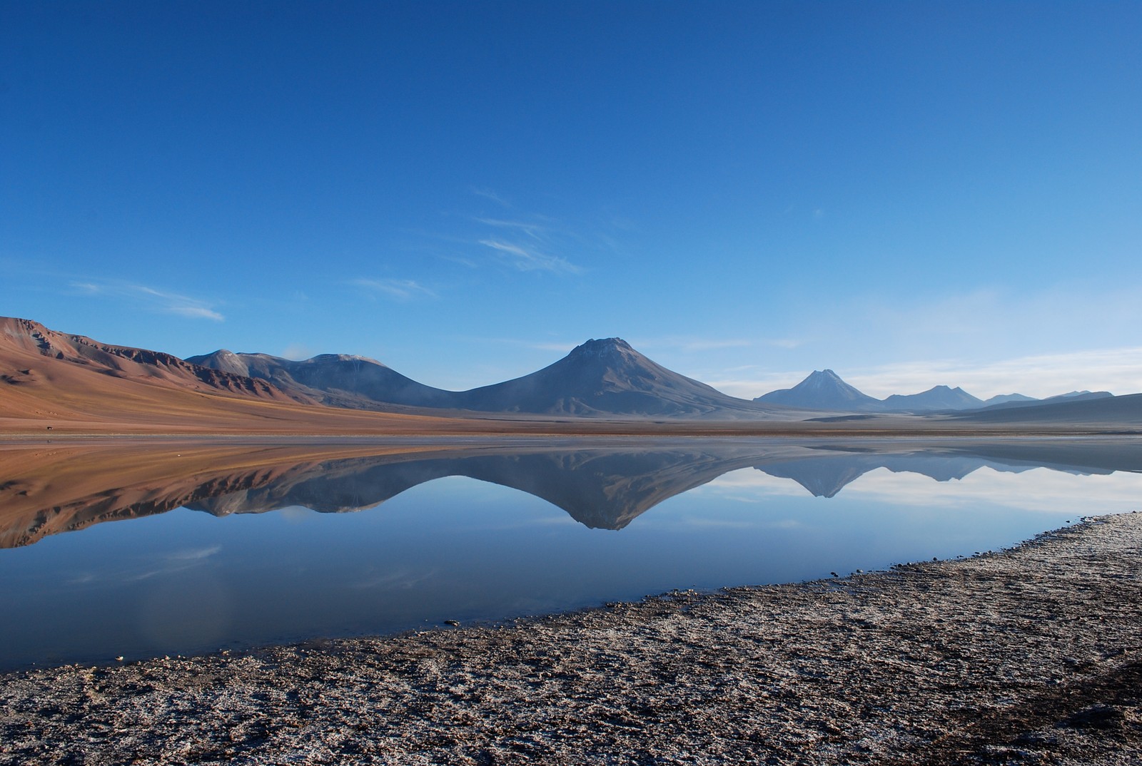 Arafed mountain range reflected in a lake with a clear sky (reflection, volcano, mountain, lake, wilderness)