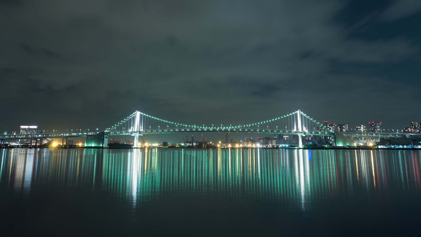 Uma bela vista de uma ponte sobre um corpo d'água à noite (ponte, noite, água, marco, céu)