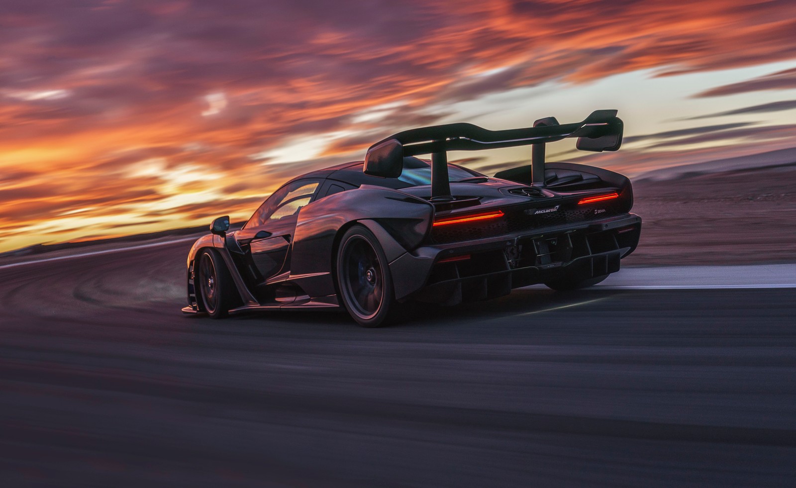 A black sports car driving on a track at sunset (mclaren senna, mclaren automotive, mclaren, car, supercar)