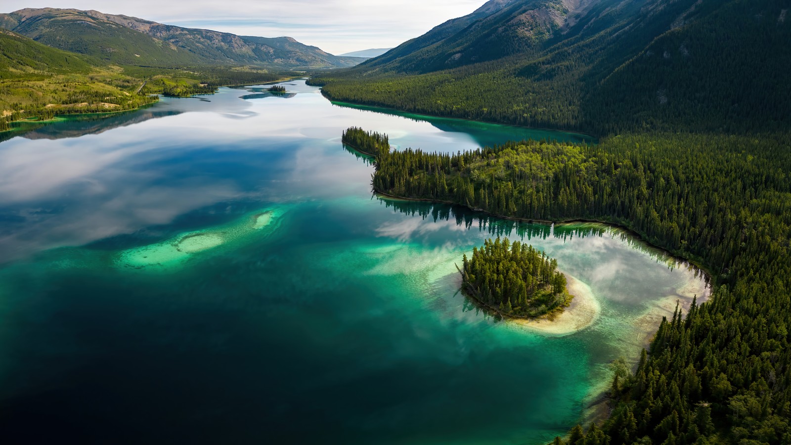 A view of a lake surrounded by trees and mountains (forest, river, nature, aerial view, scenery)