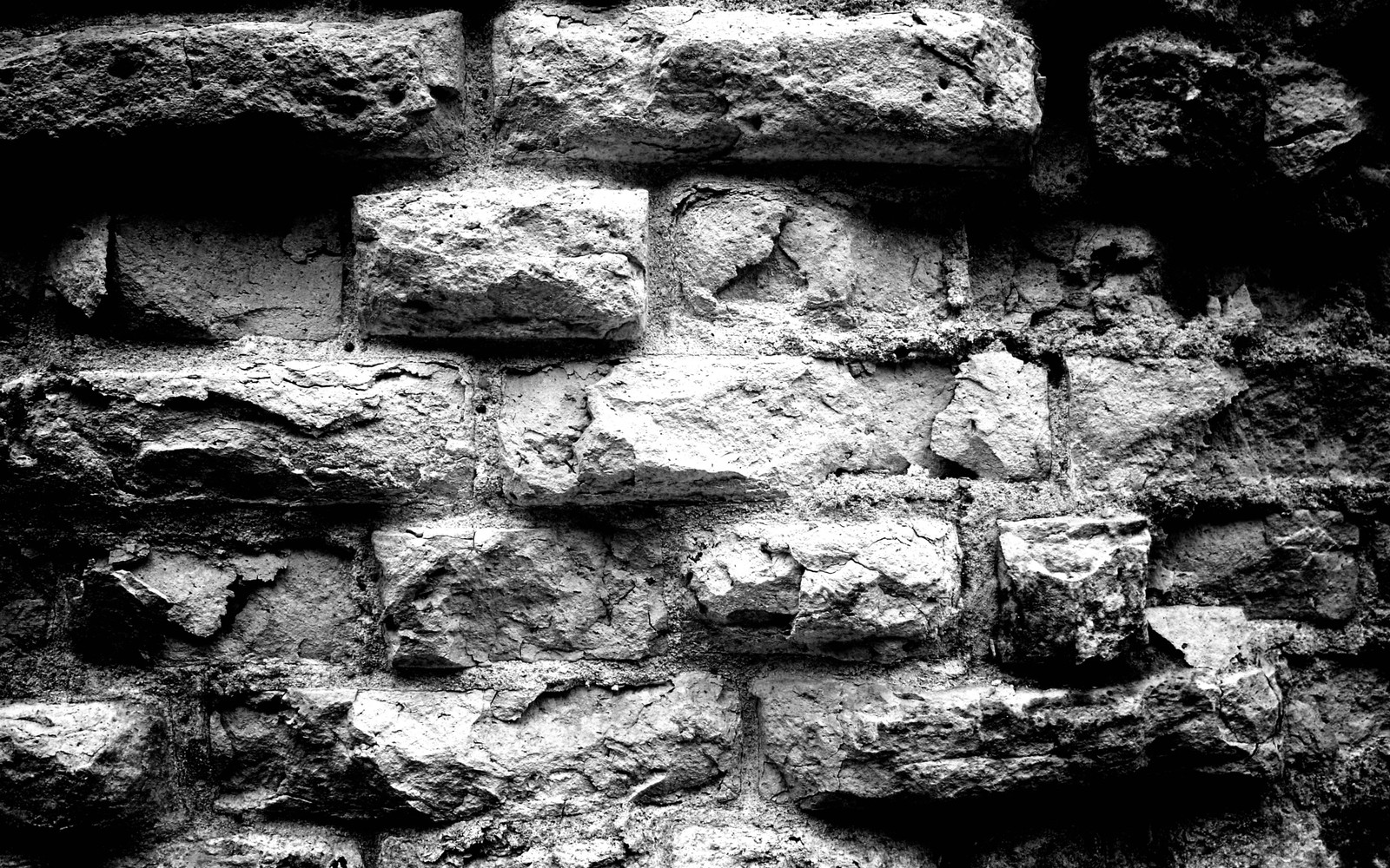 Un primer plano de una foto en blanco y negro de una pared de ladrillo (pared, muro de piedra, ladrillo, roca, geología)