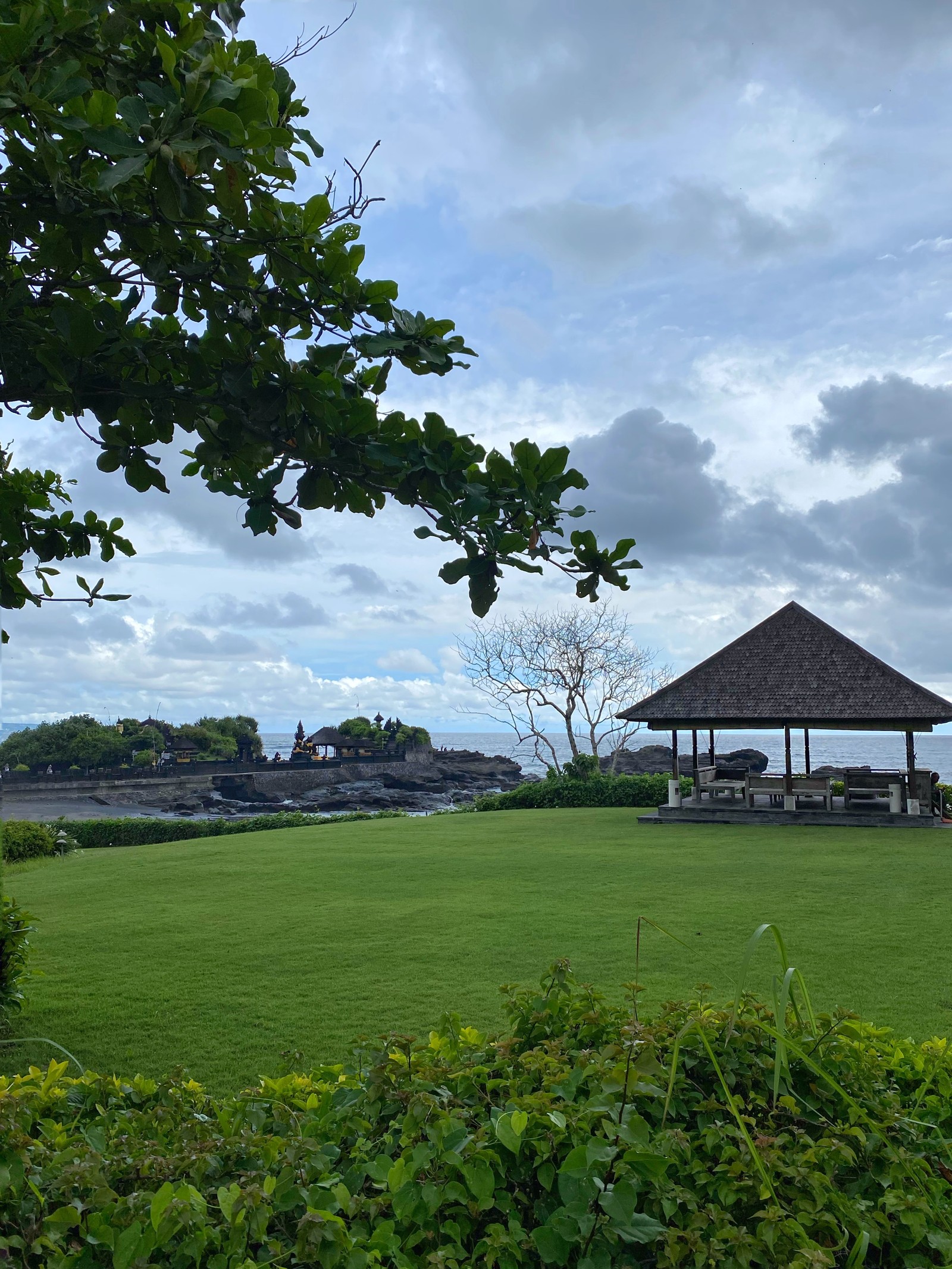 There is a gazebo in the middle of a grassy field (bali, cloud, land lot, plain, roof)