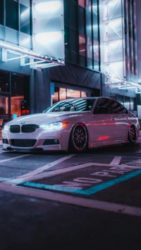 Sleek sedán BMW M3 estacionado bajo las vibrantes luces de la ciudad, mostrando su diseño moderno y características de rendimiento.