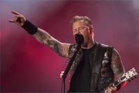 James Hetfield of Metallica delivers a powerful performance, passionately singing into a microphone with a guitar in hand, captivating the crowd in Rio de Janeiro.