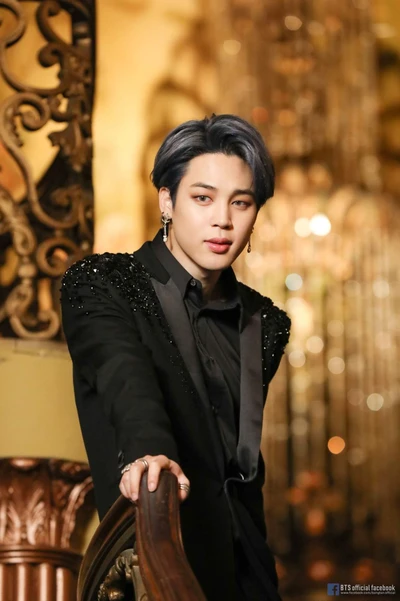 Jimin do BTS em um traje preto estiloso contra um fundo elegante.