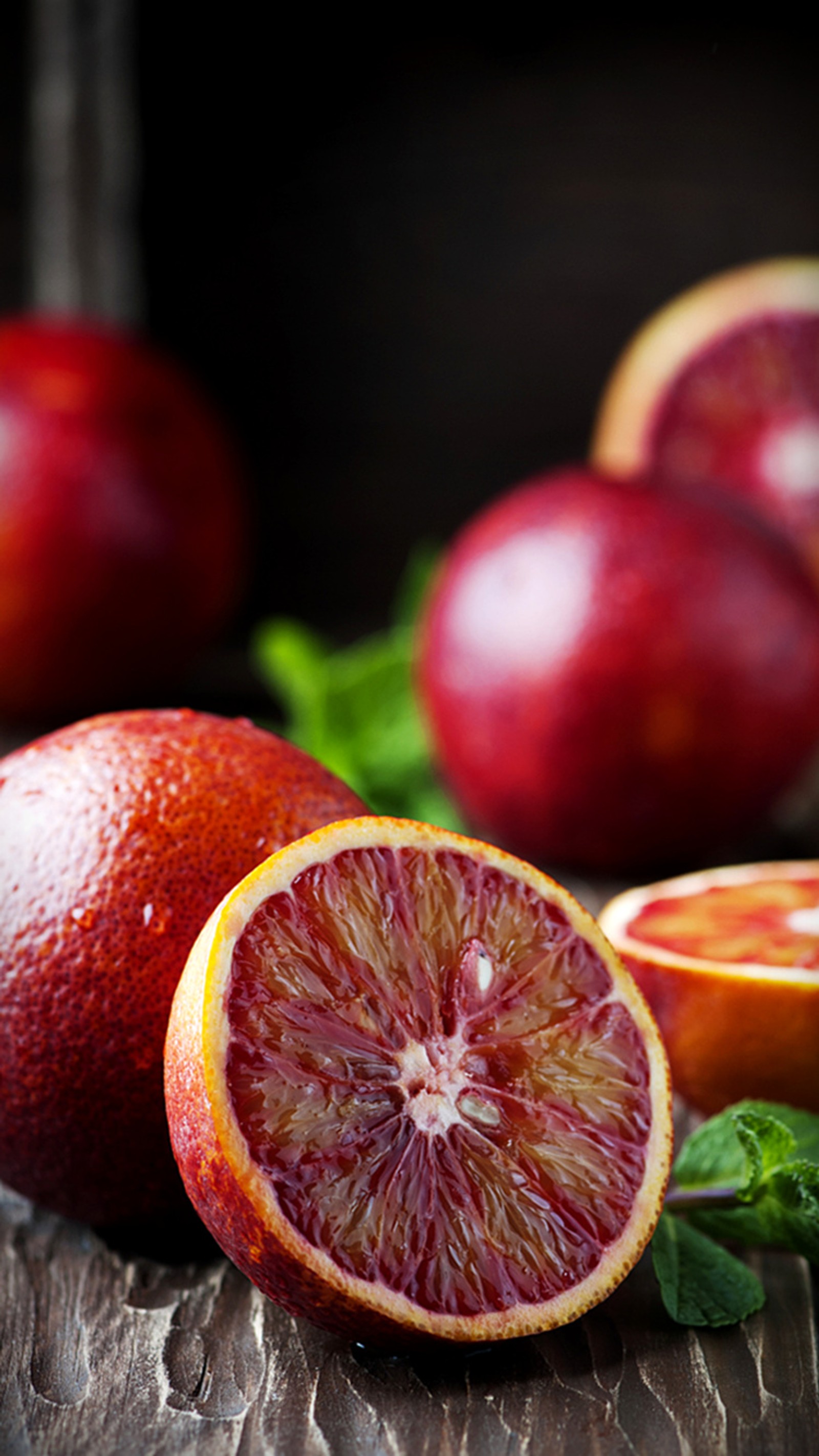 Il y a des oranges sanguines et une orange coupée en deux sur une table. (fruits, oranges, rouge, été)