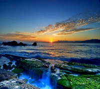 Serene Sunset Over Ocean Waves and Rocky Shoreline