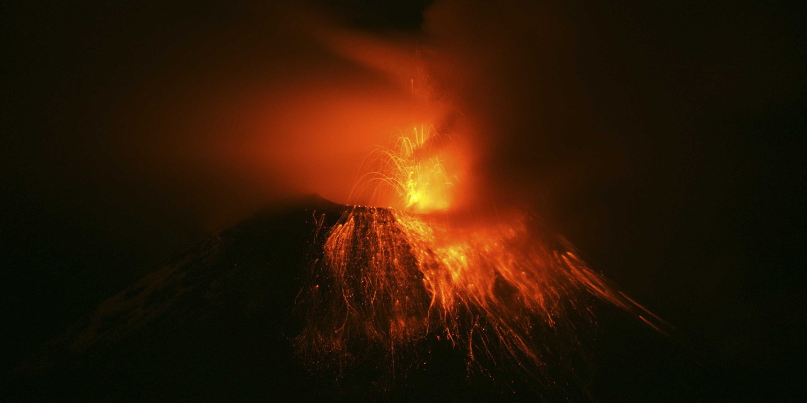 Un volcan avec un panache de lave et une personne debout dessus (types déruptions volcaniques, volcan, lave, volcan bouclier, stratovolcan)