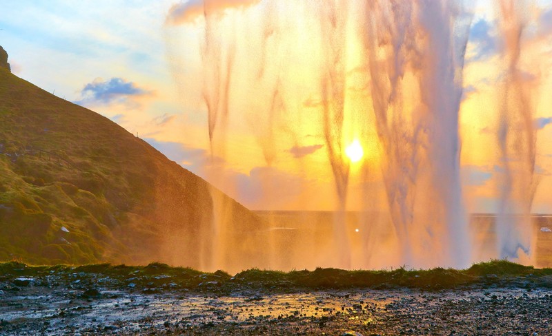 Nahaufnahme eines brunnens mit einem sonnenuntergang im hintergrund (seljalandsfoss, wasserfall, sonnenuntergang, natur, wasser)