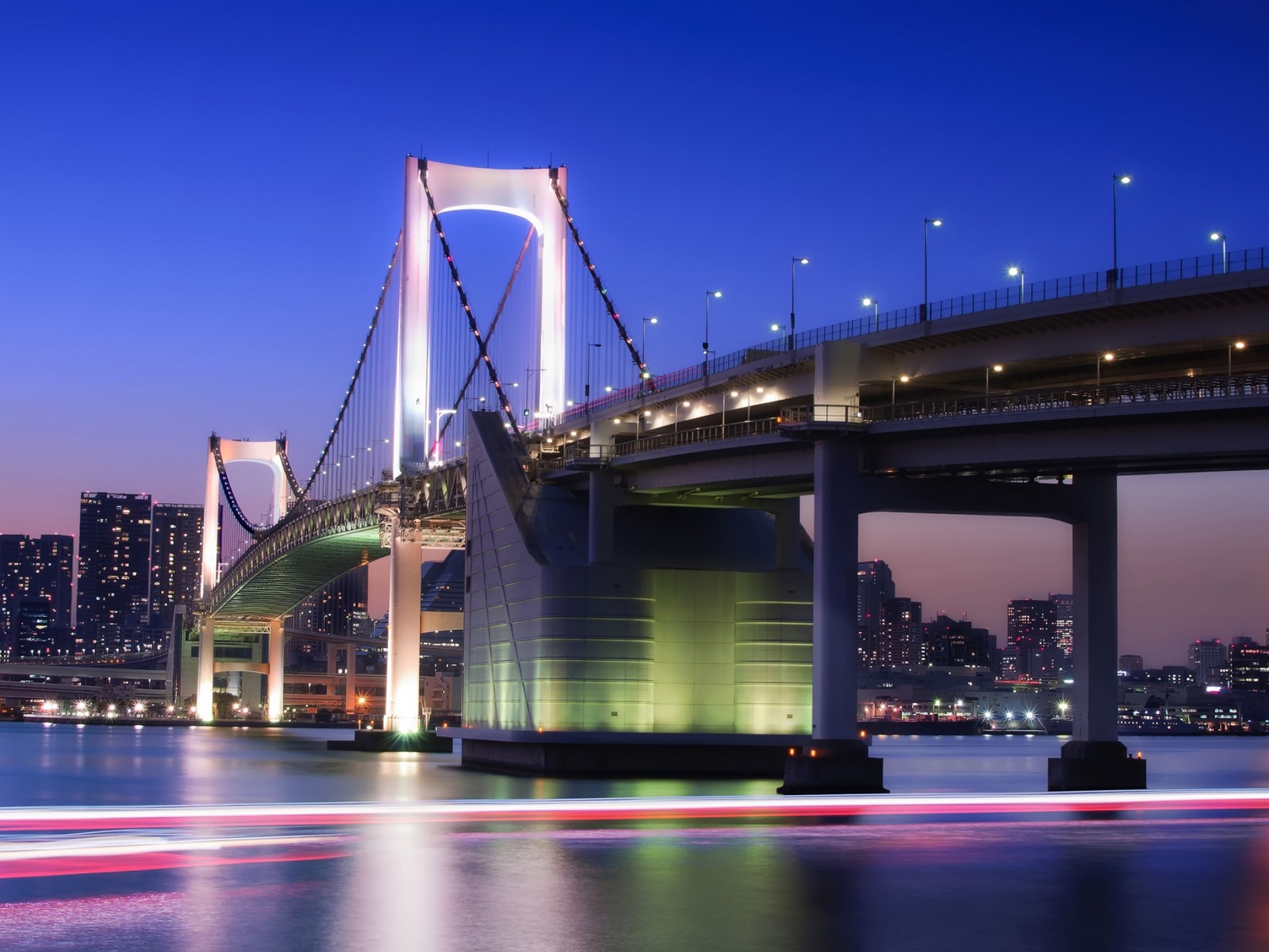 Uma ponte sobre a água com uma cidade ao fundo (ponte arco íris, ponte suspensa, ponte, ponte estaiada, marco)