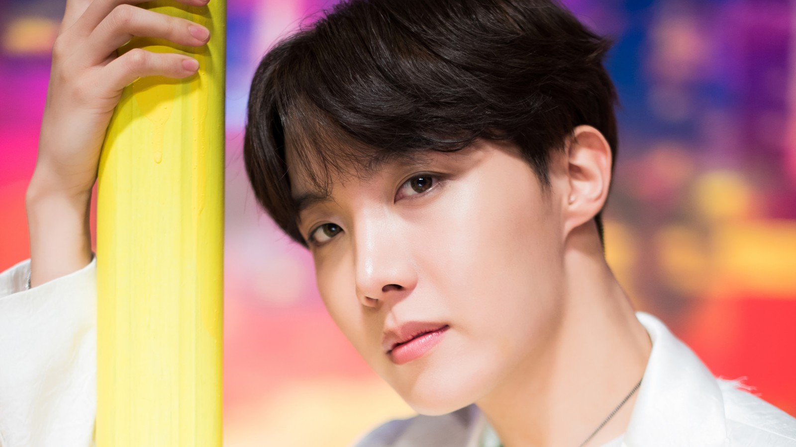 Image arabe d'un homme tenant un poteau jaune devant un fond coloré (j hope, 정호석, jung ho seok, bts, bangtan boys)