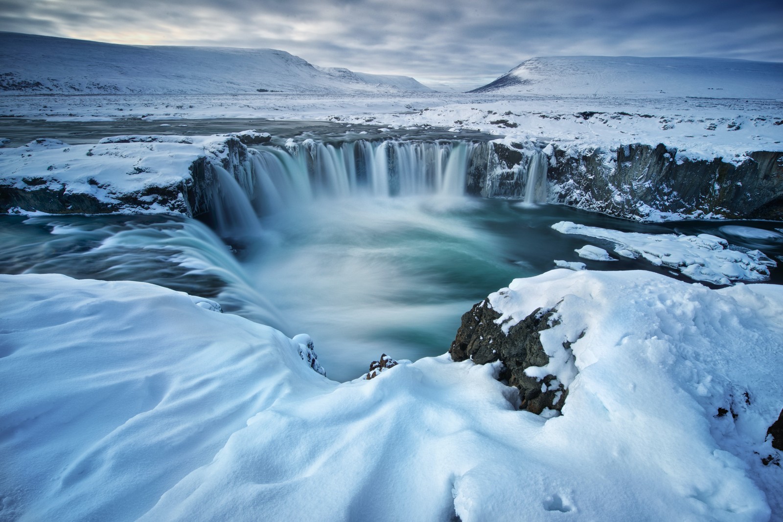 Uma cachoeira no meio de uma paisagem nevada com neve no chão (círculo dourado, seljalandsfoss, água, nuvem, atmosfera)