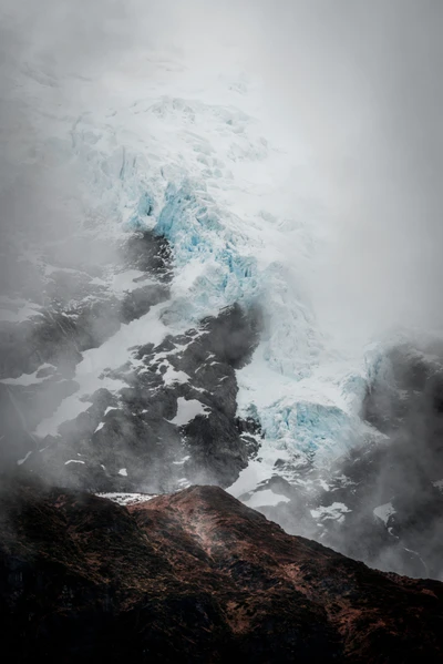 Majestätischer Gletscher zwischen nebligen Bergen und Wolken