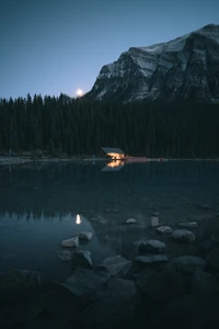 Cabana serena à beira do lago ao crepúsculo com reflexos das montanhas