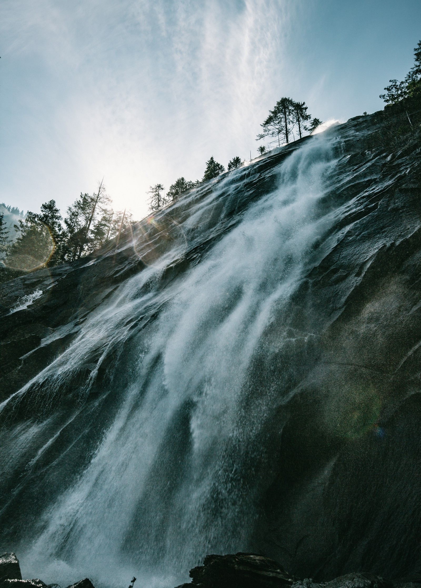 There is a waterfall that is flowing down a mountain side (body of water, water resources, waterfall, water, nature)