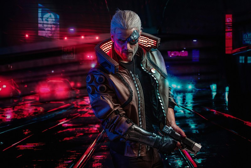 Мужчина в кожаном жакете держит пистолет в темной комнате (cyberpunk 2077, геральт из ривии, geralt of rivia, ведьмак, the witcher)