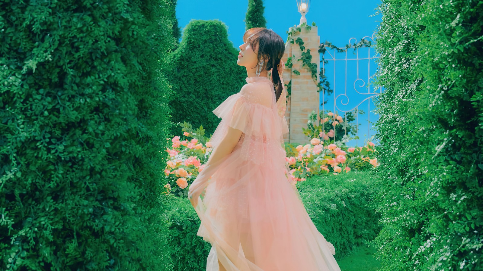 Une femme en robe rose debout dans un jardin (red velvet, kpop, 레드벨벳, le festival reve 2022, coréen)