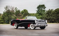 Voiture décapotable noire vintage contre un ciel nuageux