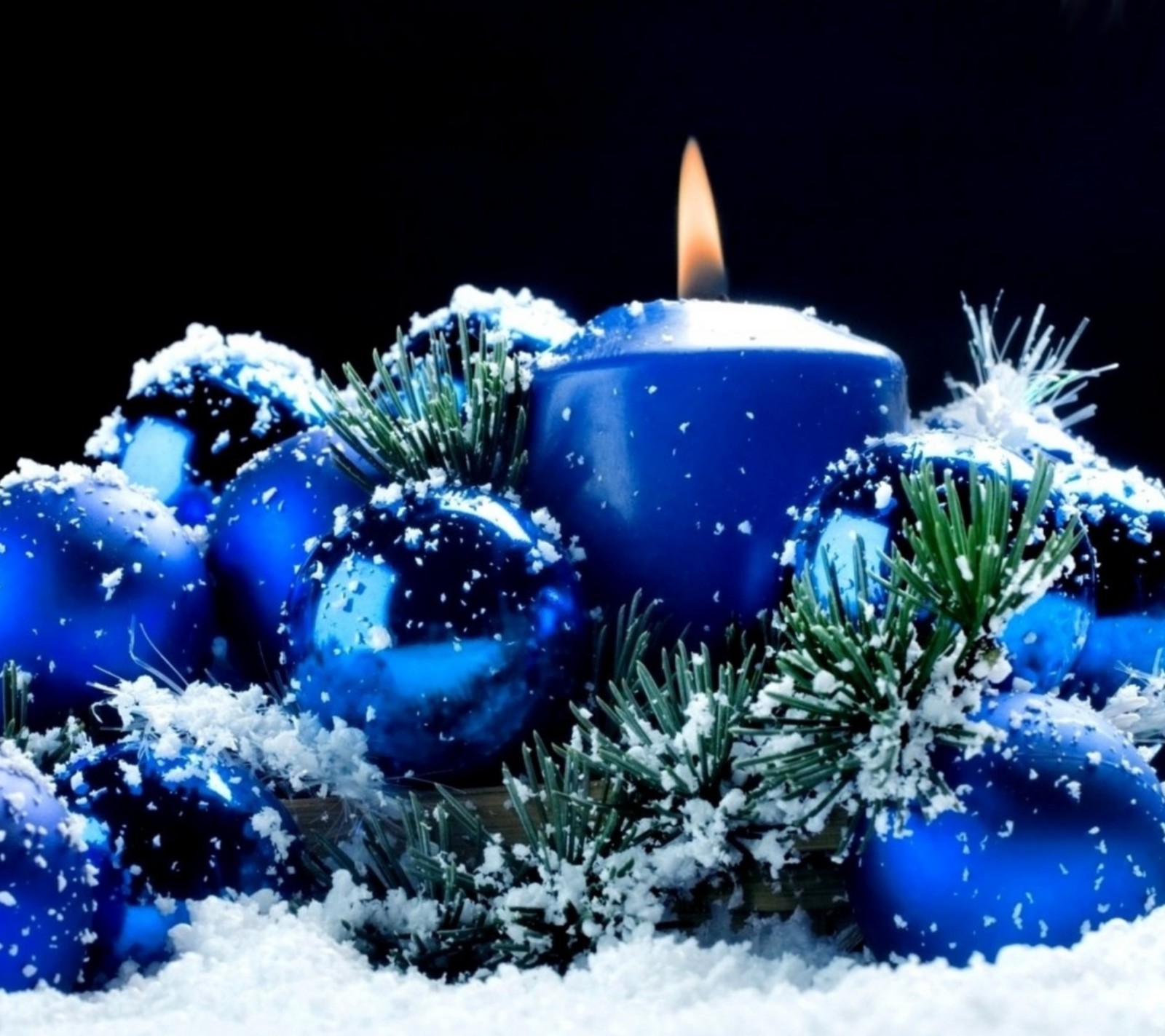 Um close de uma vela cercada por ornamentos azuis na neve (blue candle, enfeite de natal, feliz natal, natal)