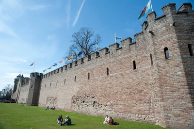 Mural histórico do castelo com visitantes em um gramado verdejante