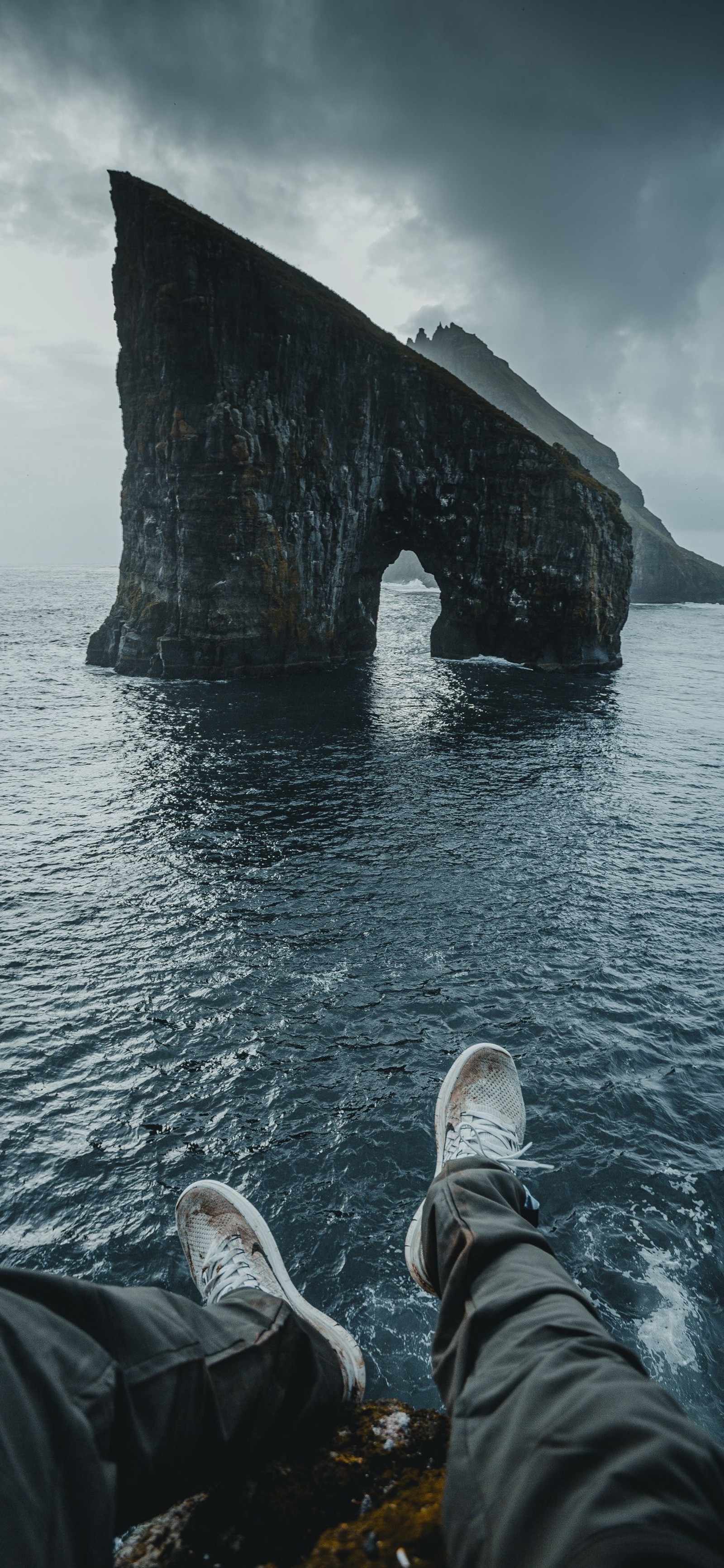 Jemand sitzt auf einem stein im wasser mit hochgelegten füßen (meer, wasser, wolke, natur, formation)