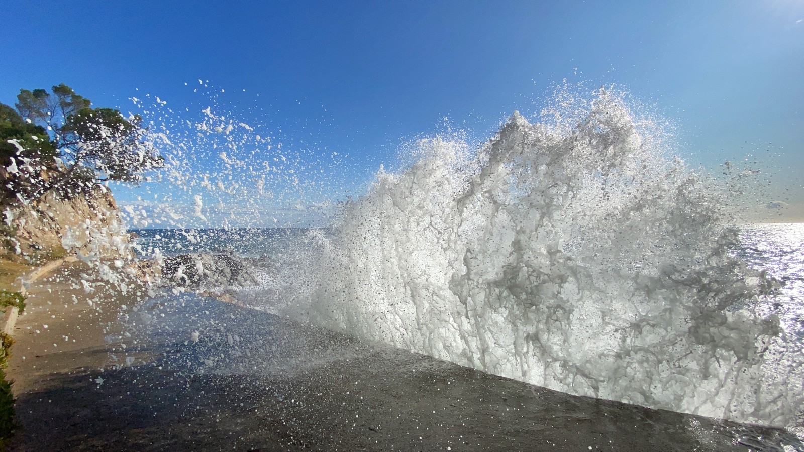 Esguichos de água espirrando em uma parede de pedra perto do oceano (água, ciência, líquido, azul, dia)