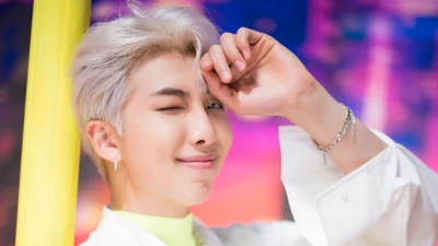 RM из BTS игриво подмигивает на фоне ярких цветов