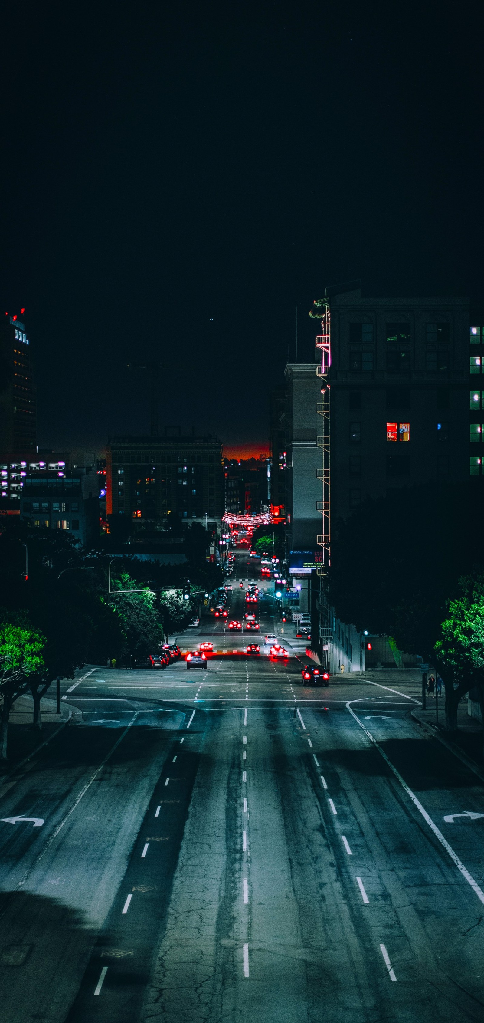 Nighttime view of a city street with cars driving on it (cars, light fixture, darkness, street light, traffic)