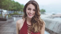 Celine Farach sonriendo en un elegante traje de baño rojo junto al agua