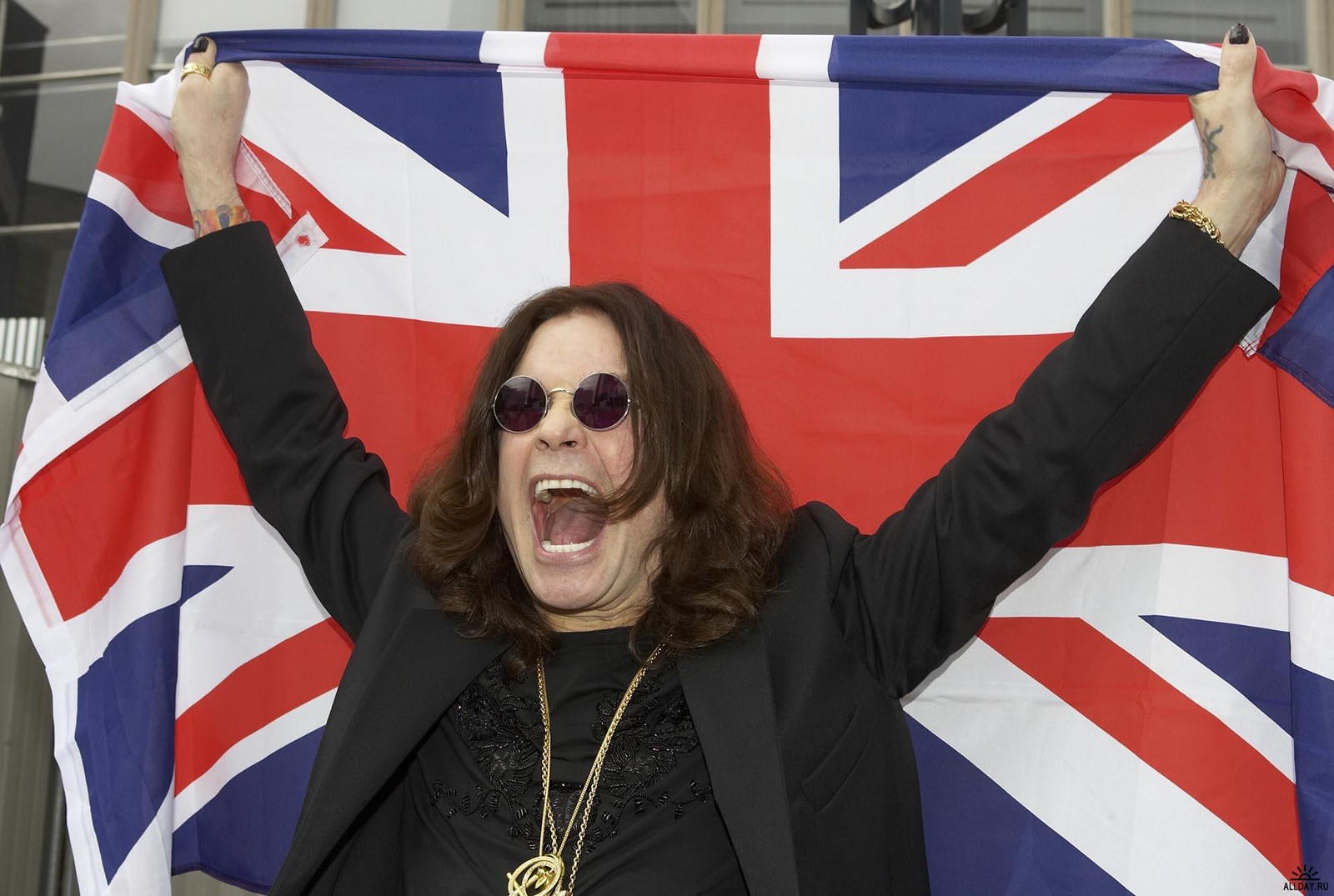 Una mujer sosteniendo una bandera británica y una medalla de oro (ozzy osbourne, black sabbath, bandera, evento, artista)