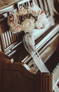 Bouquet de mariée élégant orné de dentelle, reposant sur une surface en bois, entouré de douces teintes florales.