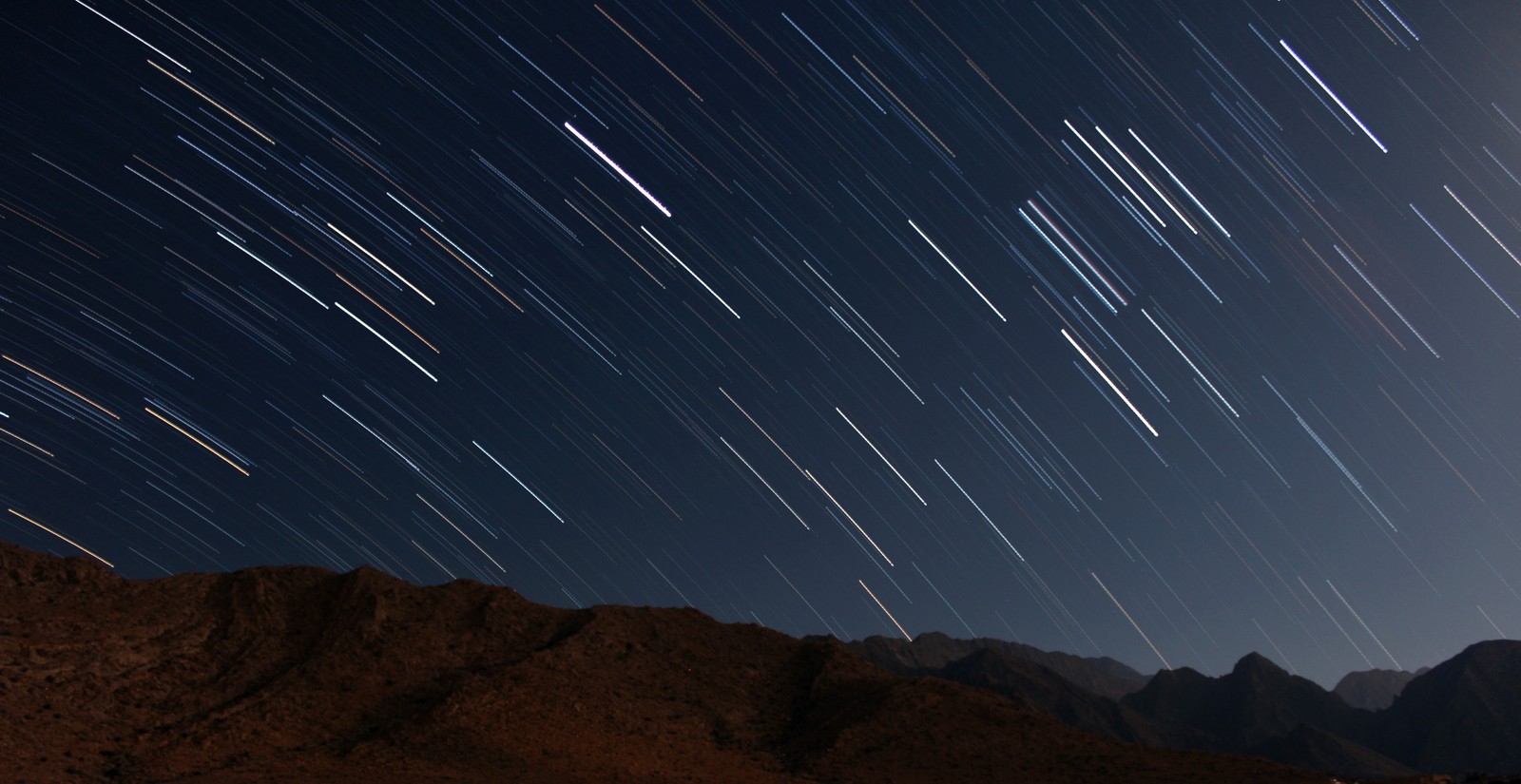 Un primer plano de una montaña con un rastro de estrellas en el cielo (estrella, cielo nocturno, astronomía, objeto astronómico, atmósfera)