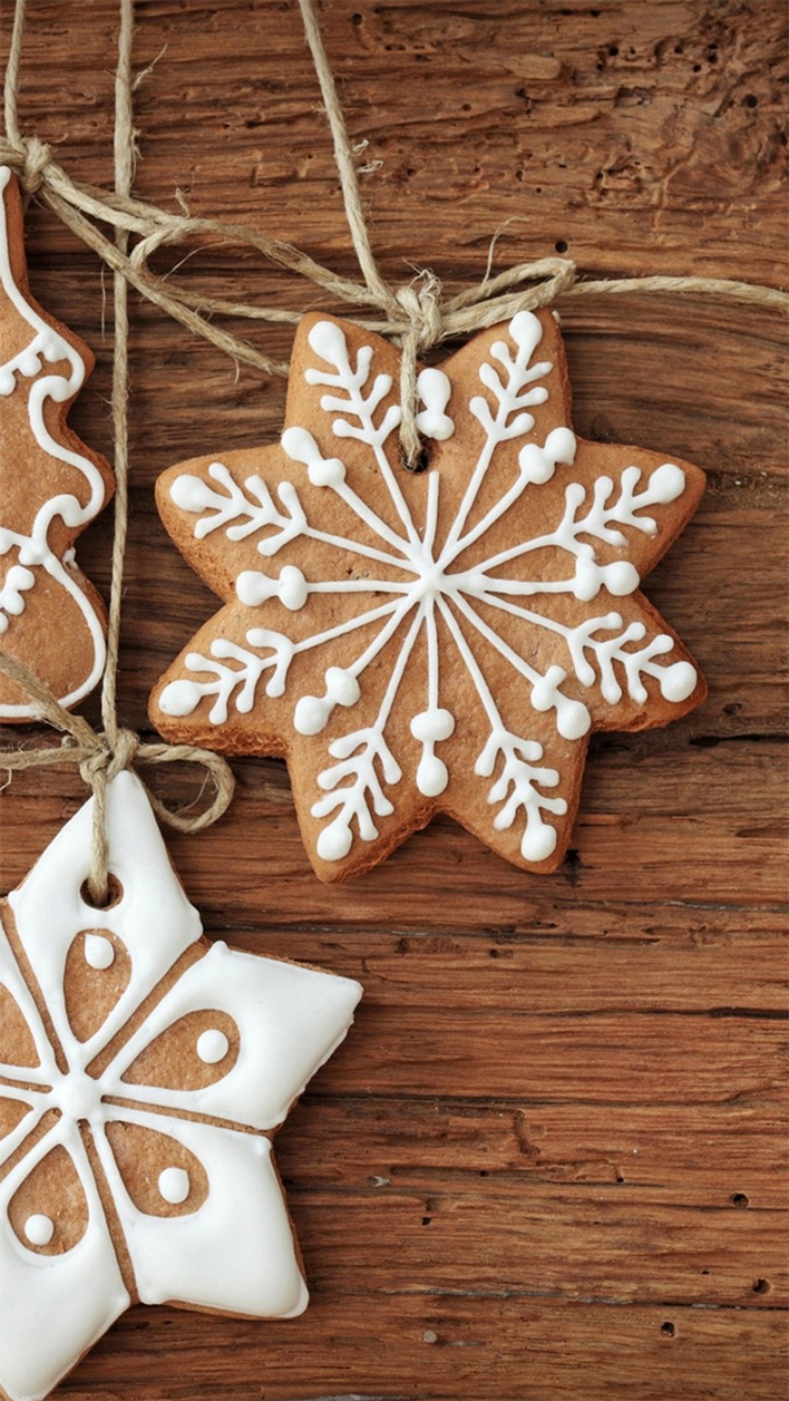 Tres galletas decoradas colgando de un hilo sobre una mesa de madera (navidad, pan de jengibre, dulces)