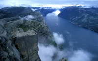 Impresionante vista aérea del acantilado Trolltunga con vistas a un fiordo sereno y un terreno montañoso accidentado.