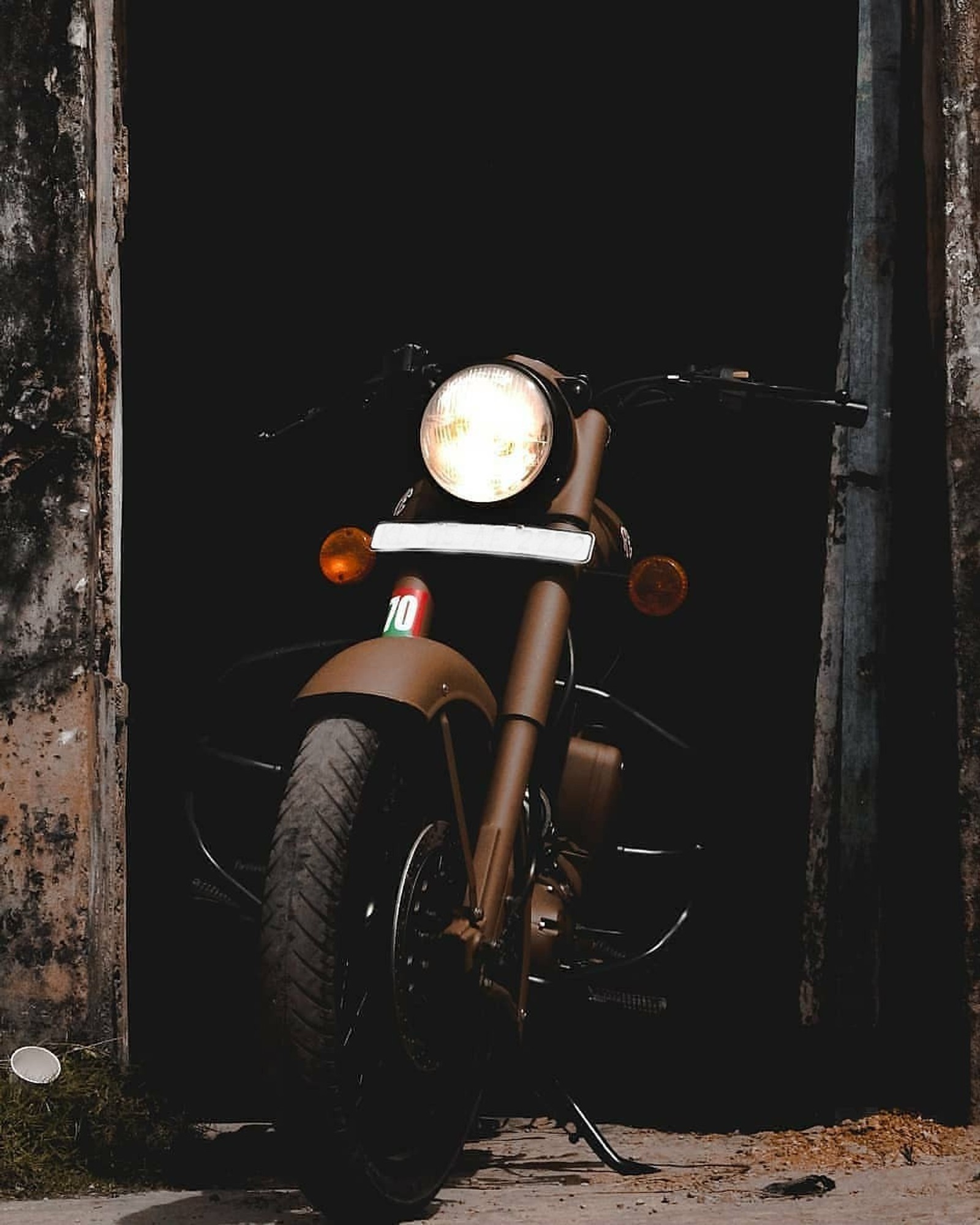 There is a motorcycle parked in a doorway of a building (royal enfield, classic, 350, 500, storm rider sand)