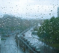 Des gouttes de pluie sur une vitre, floutant le paysage d'hiver à l'extérieur.