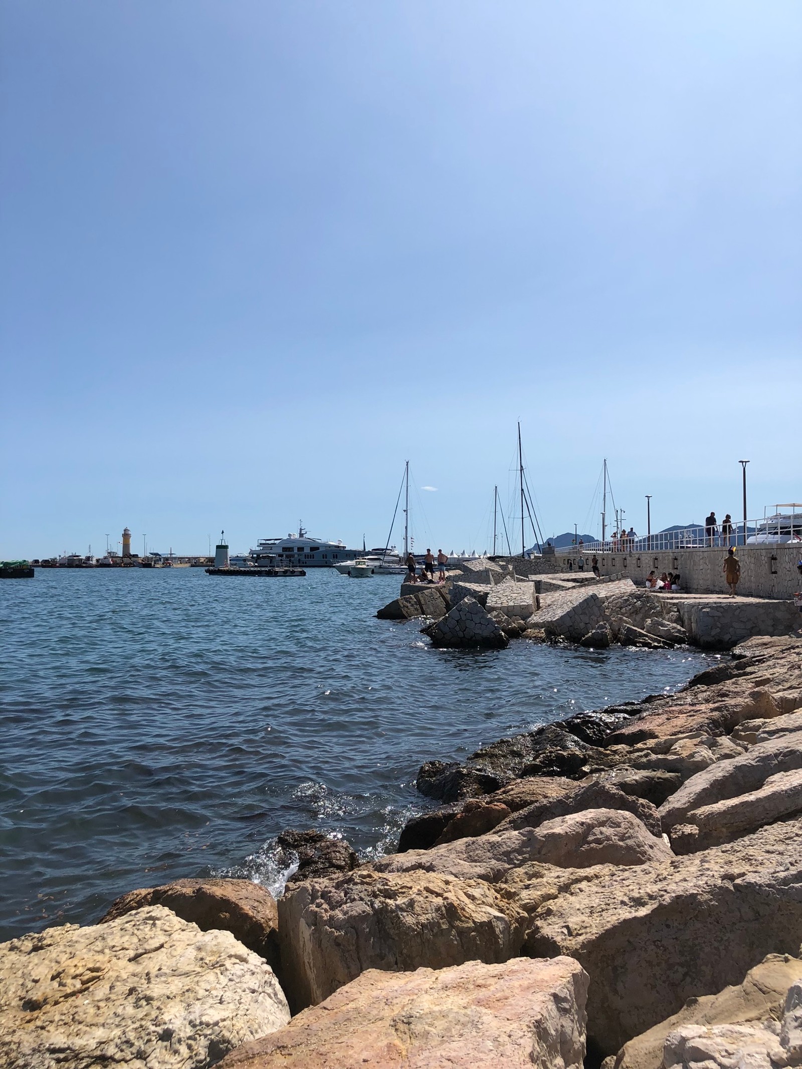 There is a man standing on a rock wall by the water (sea, rock, bank, shore, bedrock)