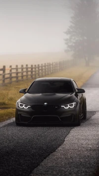 Sleek black BMW M4 on a misty road, highlighting its aggressive stance and distinctive headlights.