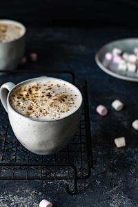 Cappuccino with marshmallows on a wire rack, set against a dark backdrop.