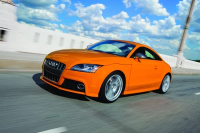 Lebendiges orangefarbenes Audi TT Sportauto in Bewegung vor einer malerischen Kulisse